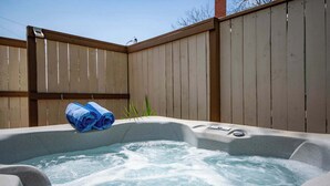 Ein Whirlpool mit Wasser, ein Holzzaun und ein aufgerolltes Handtuch.
