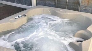 Un bain à remous rempli d’eau, entouré d’une clôture métallique.