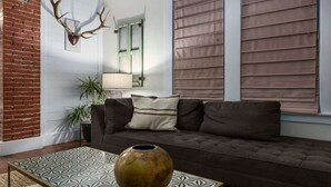Un salon chaleureux avec un canapé marron, un tapis à motifs et un vase décoratif.