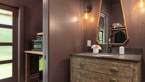 Ein Badezimmer mit einem Holzkosmetikschrank, einem großen Spiegel und einer wandmontierten Leuchte.