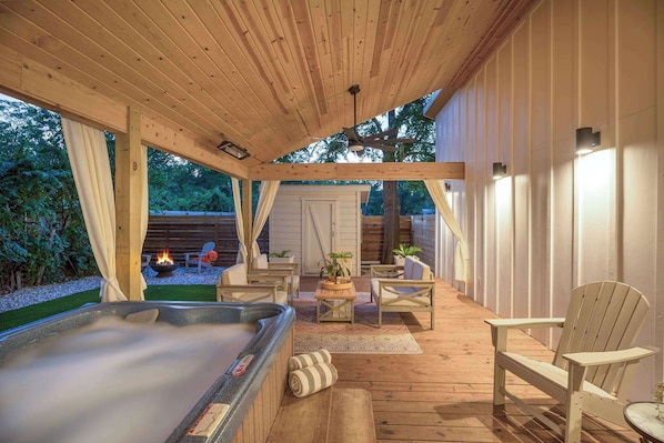A wooden deck with a hot tub, chairs, and a fire pit.