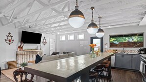Een ruime keuken met een groot kookeiland, barstoelen en hanglampen.
