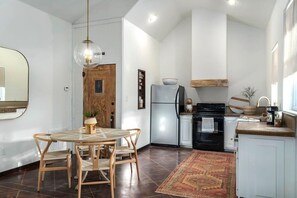 A modern kitchen with a round dining table, wooden chairs, a refrigerator, and a stove.