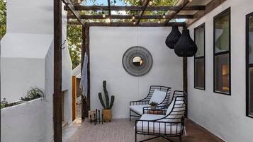 A covered outdoor seating area with a pergola, a round mirror, and hanging pendant lights.