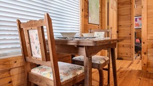 Un intérieur en bois avec une table en bois et une chaise recouverte d’un tissu à motifs floraux.
