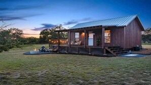 A rustic cabin with a porch, outdoor seating, and a fire pit.