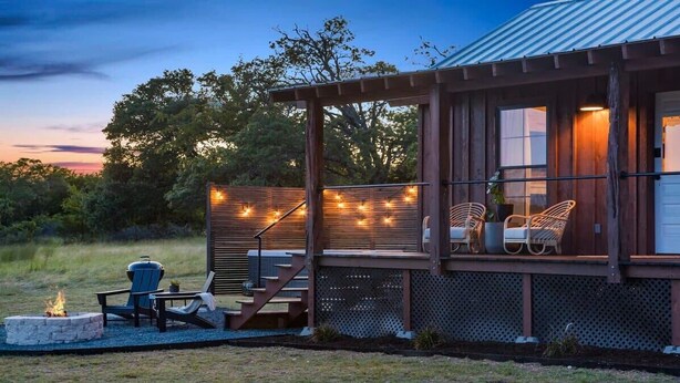 A wooden cabin with a porch, outdoor seating, and a fire pit.