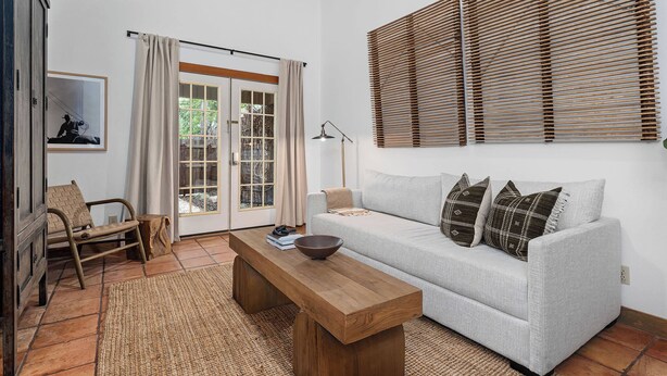 A living room with a sofa, a wooden bench, a bowl, and a framed picture on the wall.