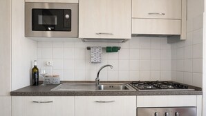 A kitchen with a Bosch microwave, a gas stove, a sink, and cabinets. - Scirocco House | Sea View Terrace (Isola Rossa)