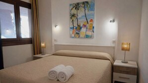 A hotel room with a bed, two bedside tables, a painting, and a window. - Scirocco House | Sea View Terrace (Isola Rossa)