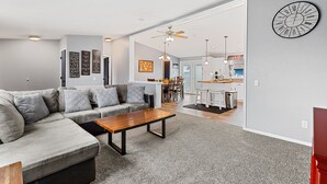 A modern living room with a sectional sofa, a wooden coffee table, and a kitchen in the background. - Located near Mt. Rushmore, the Black Hills, Badlands National Park & more!! (Hermosa)