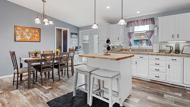 A modern kitchen with white cabinets, a wooden island, and pendant lighting. - Located near Mt. Rushmore, the Black Hills, Badlands National Park & more!! (Hermosa)