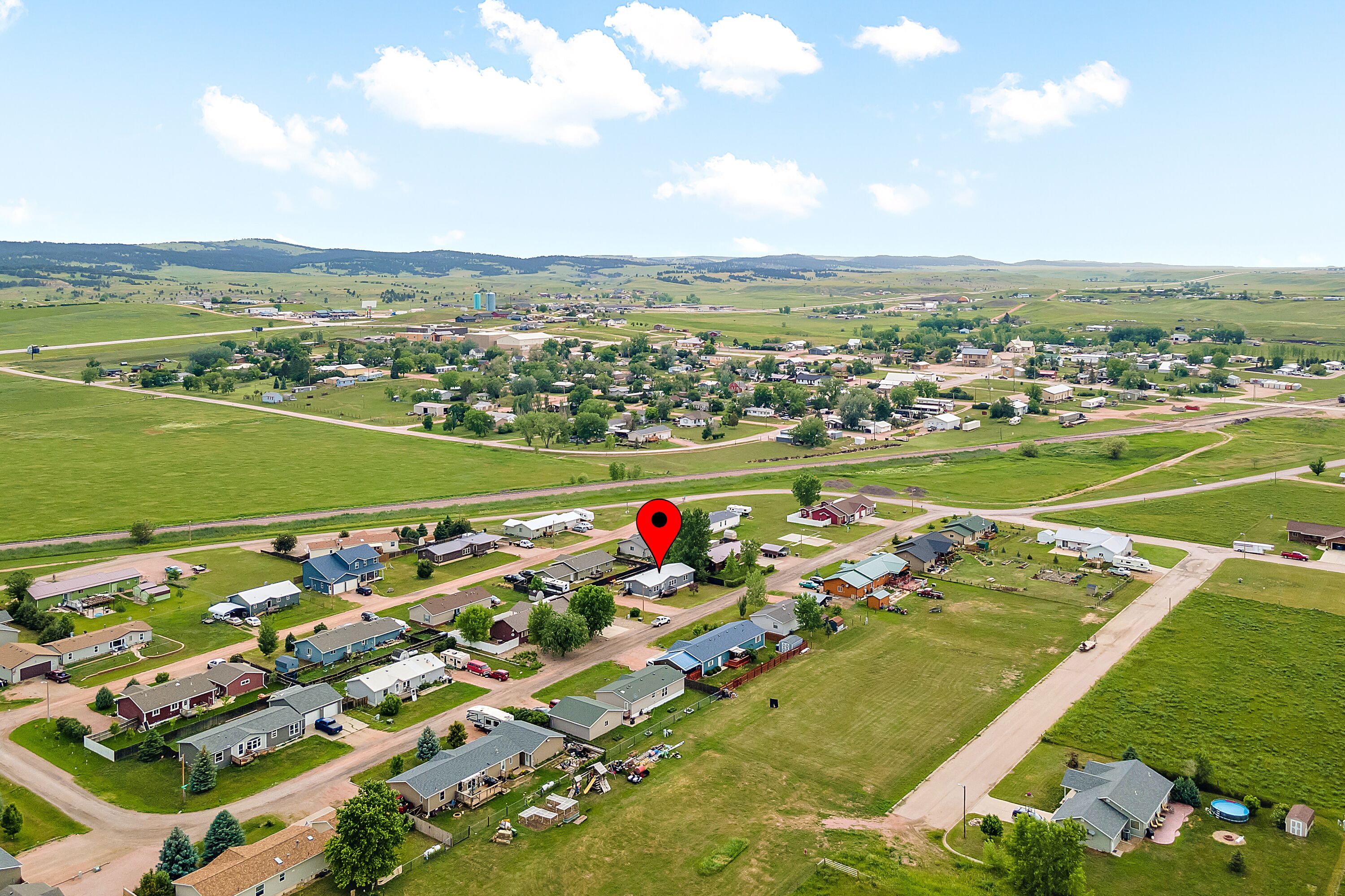 An aerial view of a residential area with houses, roads, and green fields.