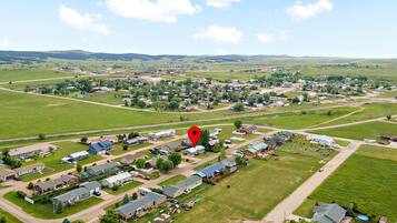 An aerial view of a residential area with houses, roads, and green fields.