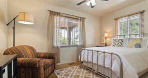 Une chambre à coucher avec un lit, une chaise, une lampe et un ventilateur de plafond.