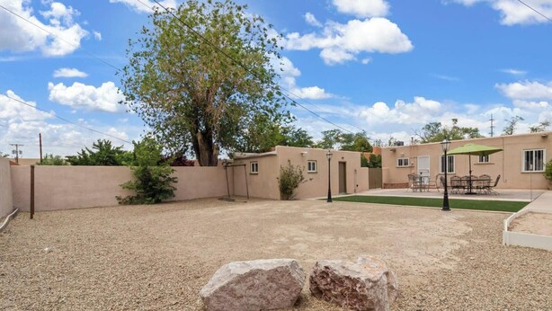 A residential area with a house, a patio with outdoor furniture, and a tree. - The Dartmouth House S (Albuquerque)