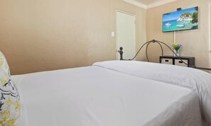 A hotel room with a bed, a television mounted on the wall, and a door. - The Dartmouth House S (Albuquerque)