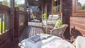 Un terrazzo in legno con un divano, sedie e un tavolo.