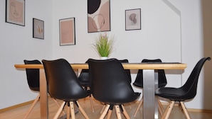 A dining area with a wooden table, black chairs, and framed artwork on the wall.