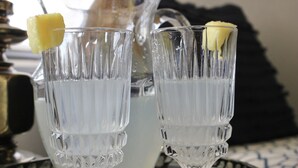 Twee glazen drinkglazen met een ananasdecoratie op een dienblad.