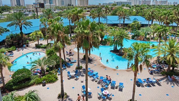A resort with multiple swimming pools, palm trees, and lounge areas. - NEW Updated Condo~HUGE Lagoon Pool~Balcony~SplashPad~Full2BR Palms Resort #1515 (Destin)