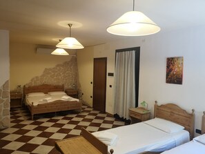 Un dormitorio con dos camas, una pared de piedra, suelo a cuadros y un cuadro en la pared.