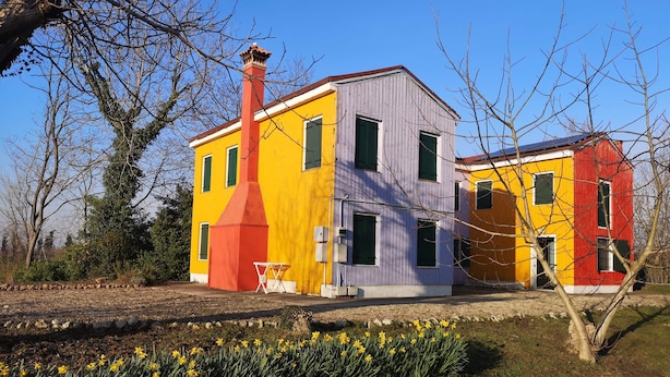 A colorful two-story house with a chimney, surrounded by a garden with daffodils. - La Via Antiga - Apartment # 1 (Torre di Mosto)