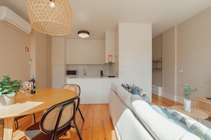 A modern kitchen with white cabinets, a dining table with chairs, and a built-in microwave. - Boavista Premium II Duplex Terrace by Vacationy (Porto)