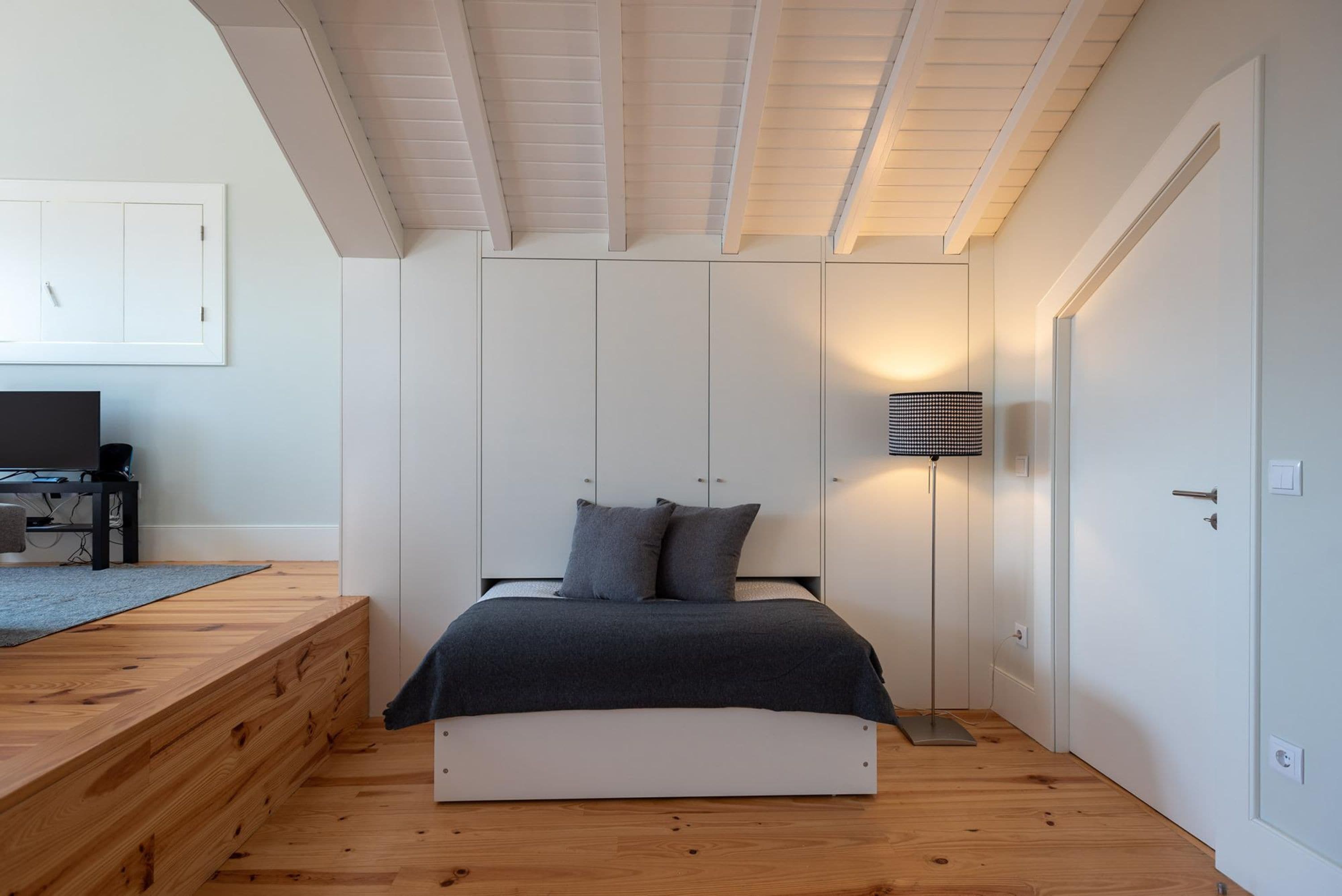 A bedroom with a bed, a desk, and a lamp.