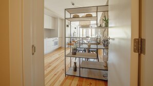 Eine moderne Küche mit Holzboden, weißen Schränken und einem Essbereich mit Tisch und Stühlen.