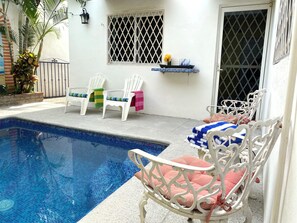 A poolside area with a pool, white chairs, and a small shelf with a flower vase. - Groundfloor 2BR with Private Pool: Palmas 3B (Bucerías)