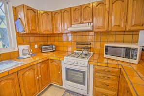 Una cocina con armarios de madera, estufa a gas, microondas y tostadora.