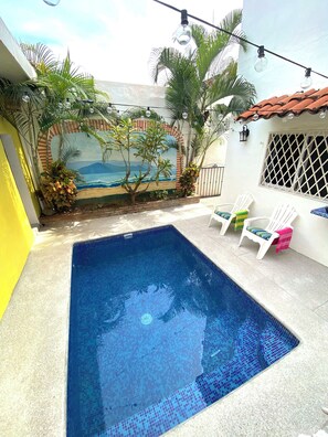 A swimming pool with a tiled deck, surrounded by chairs and a mural of a beach scene. - Groundfloor 2BR with Private Pool: Palmas 3B (Bucerías)