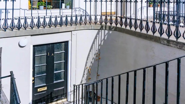 A white building with a black door and a metal railing. - Homely 3 Bedroom in the Heart of Central Edinburgh (Edinburgh)