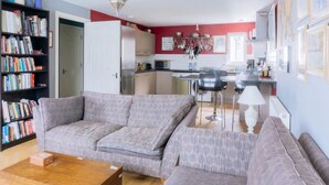 A modern living room with a grey sofa, a wooden coffee table, and a bookshelf filled with books. - Stylish 3 Bedroom Apartment Near Hollyrood Park (Edinburgh)