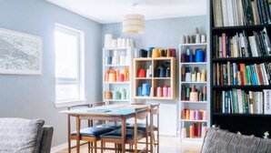 A living room with a sofa, a coffee table, a bookshelf, and a table with chairs. - Stylish 3 Bedroom Apartment Near Hollyrood Park (Edinburgh)