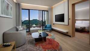 Una moderna camera d'hotel con un'ampia finestra, una TV a schermo piatto, un divano, un tavolino da caffè e un letto.