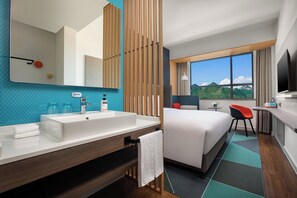 A hotel room with a large bed, a bathroom with a sink and mirror, a desk with a chair, and a window with a mountain view. - Holiday Inn Express Guiyang Qingyan by IHG (Guiyang)