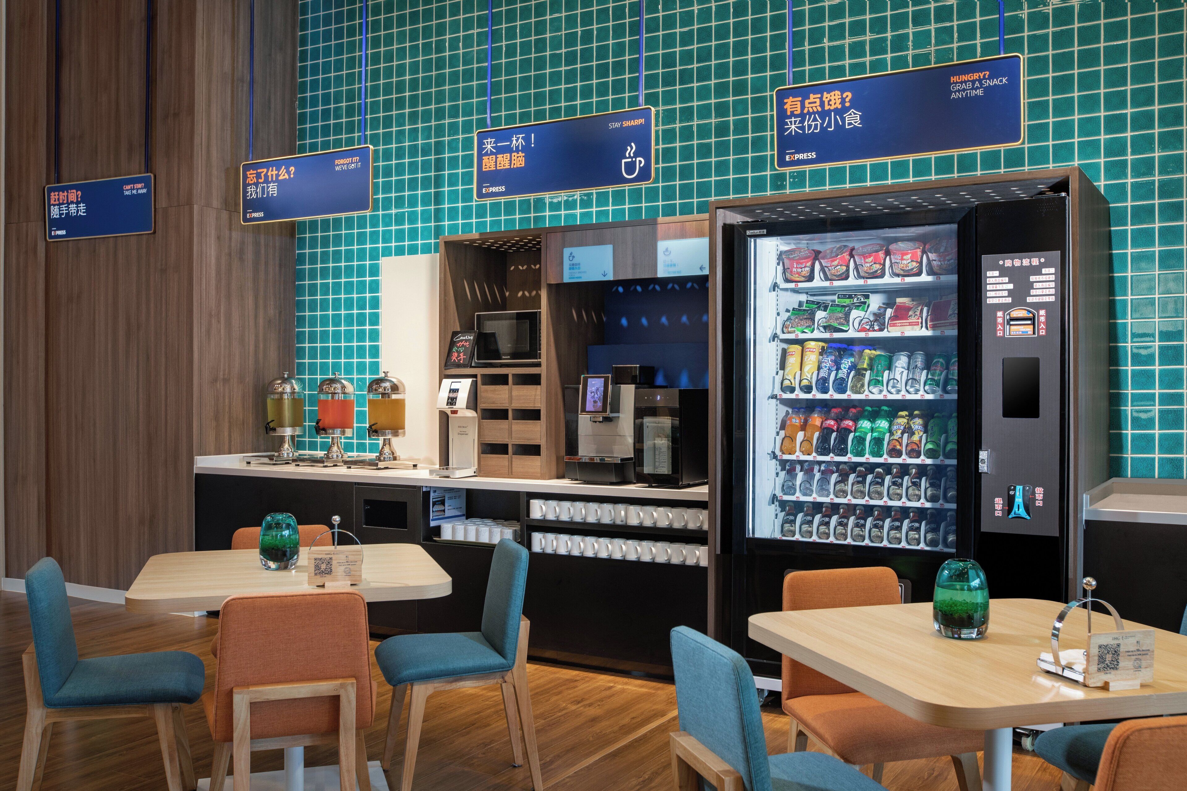 A modern cafe with tables and chairs, a coffee machine, and a vending machine.