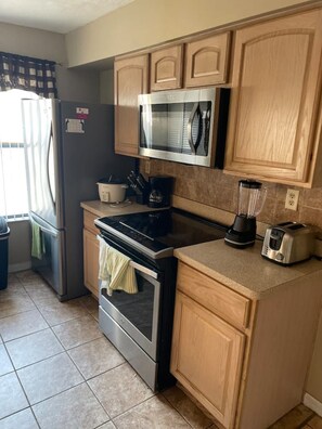 Fully equipped kitchen with refrigerator, oven, microwave, toaster, and blender.