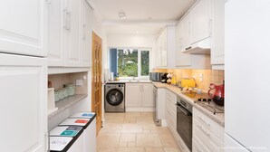 Cocina compacta con muebles blancos, lavadora, fregadero y estufa.