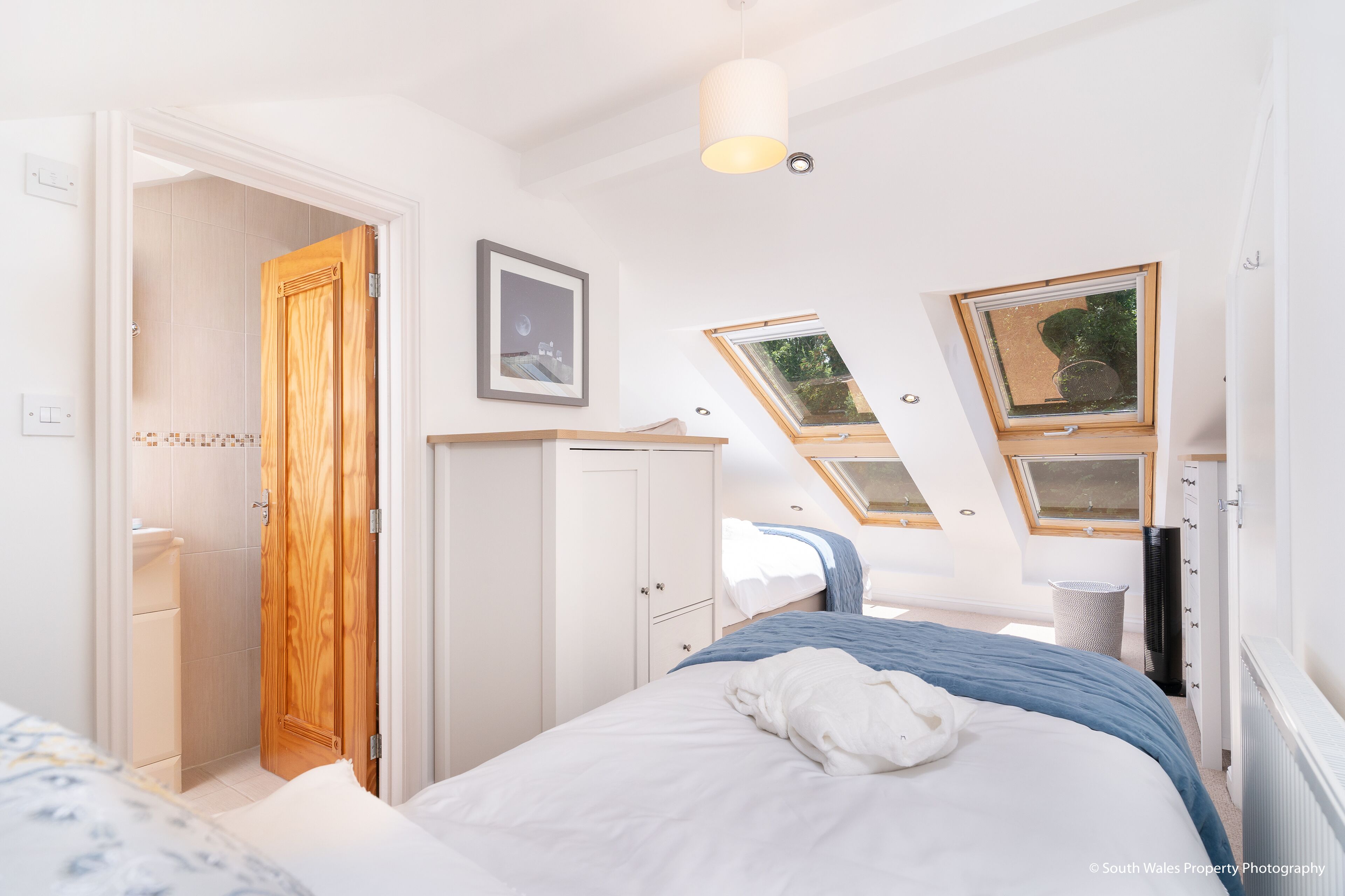 Un dormitorio con cama, armario, ventana y tragaluz.