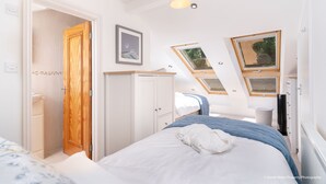 Un dormitorio con cama, armario, ventana y tragaluz.