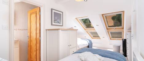 Un dormitorio con cama, armario, ventana y tragaluz.