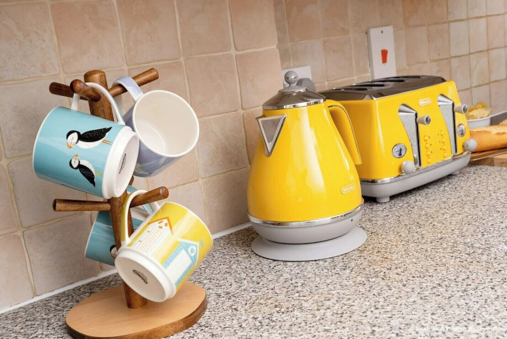 Eine Küche mit einem gelben Toaster, einer Kaffeemaschine und einem Beistellregal für Tassen.