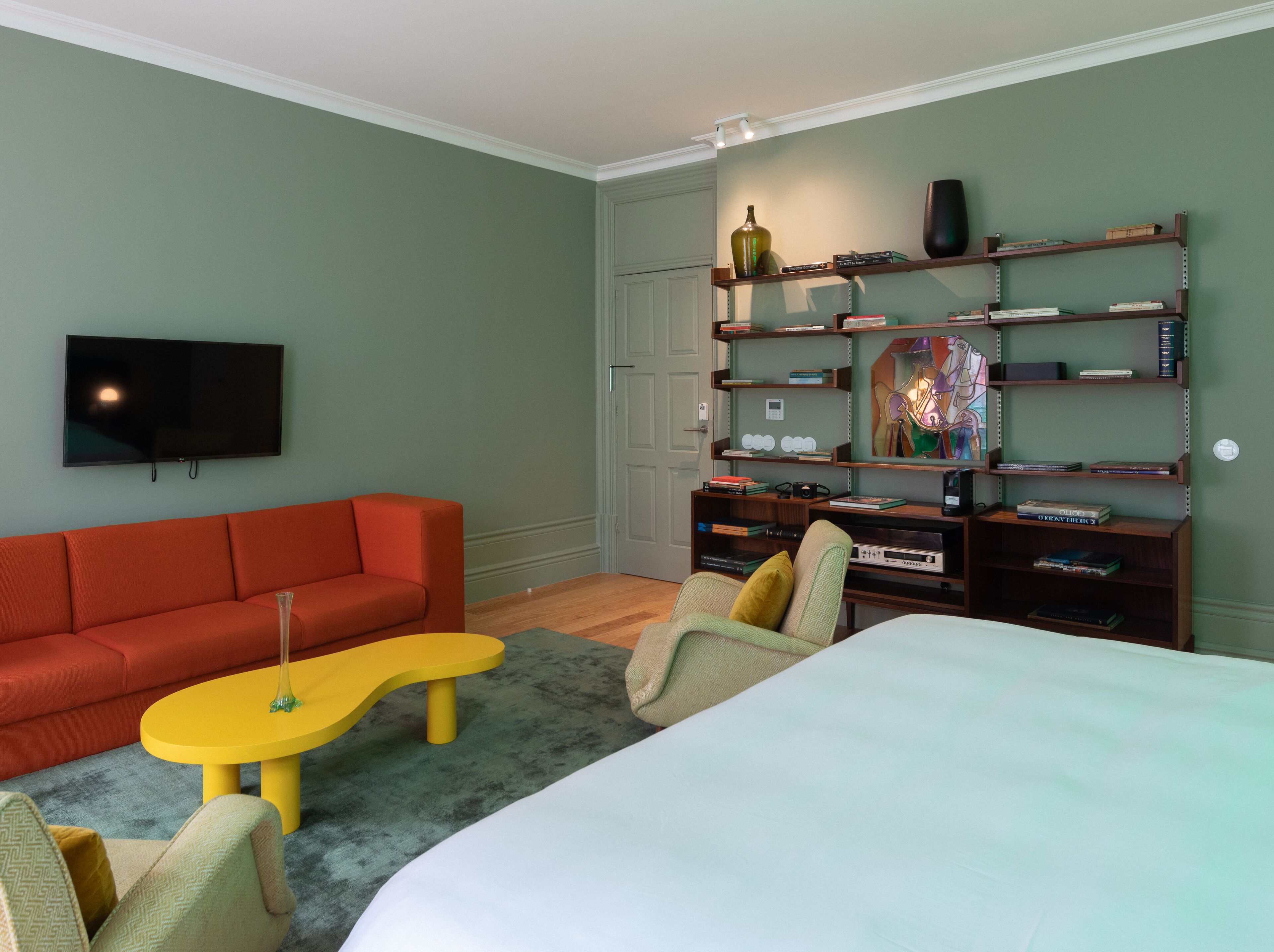 A modern living room with a red sofa, a yellow coffee table, and a bookshelf filled with books and decorative items.