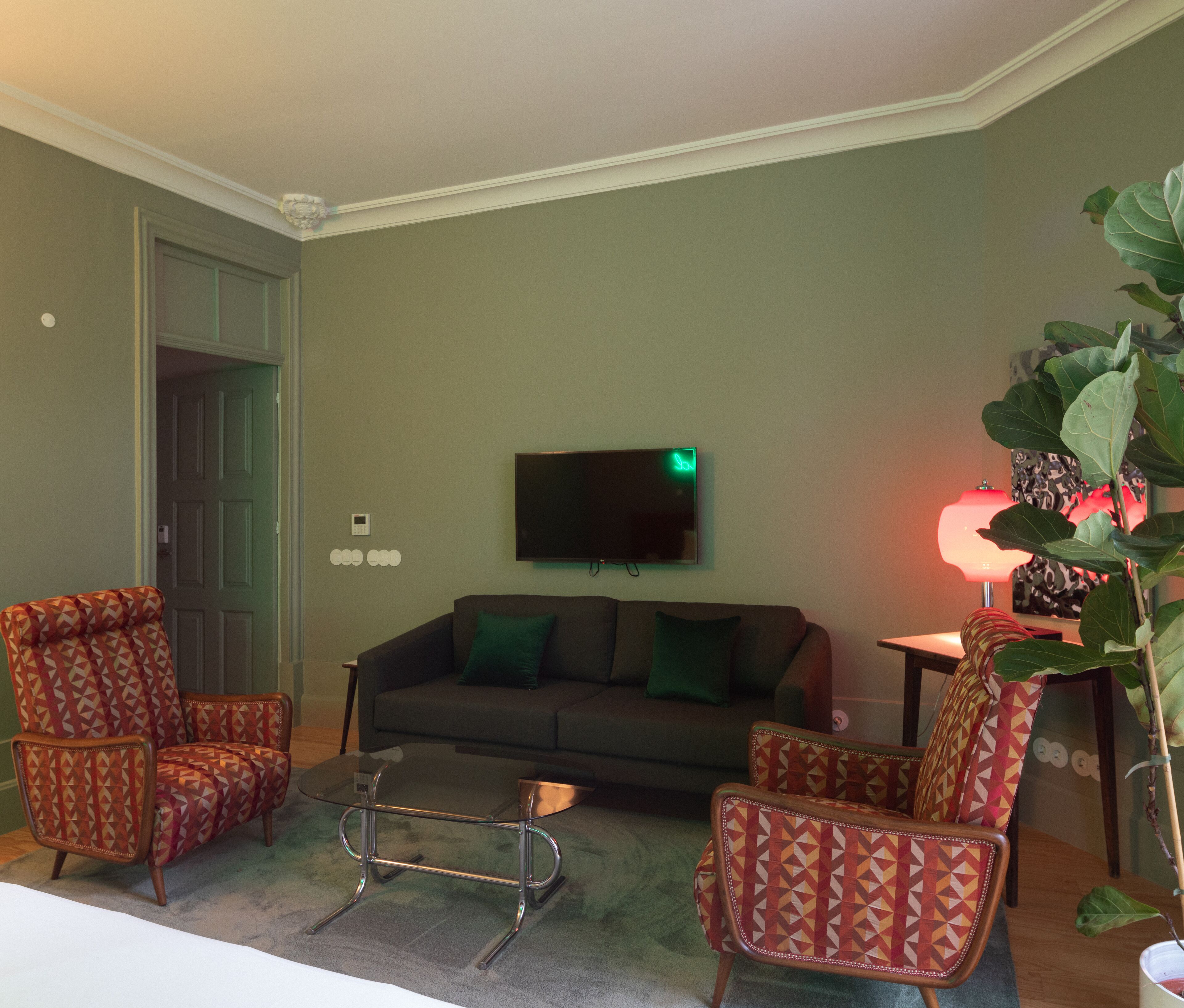 A living room with a sofa, two patterned armchairs, a coffee table, a television, and a lamp.