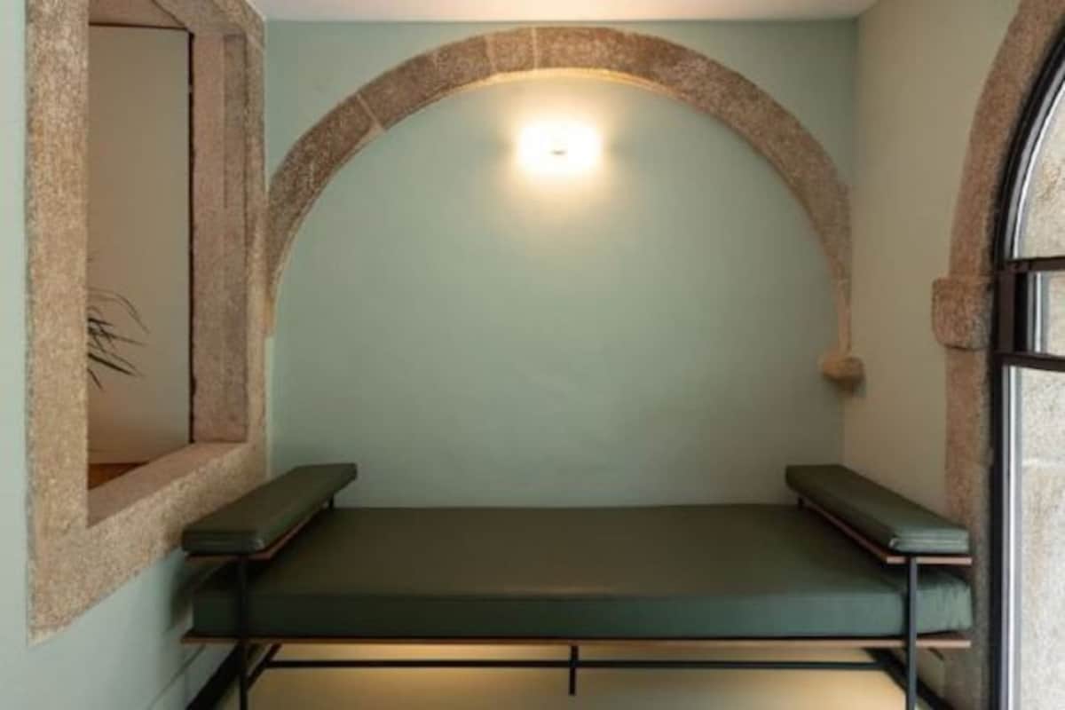 Una habitación pequeña y privada con un banco, una lámpara y arcos de piedra.