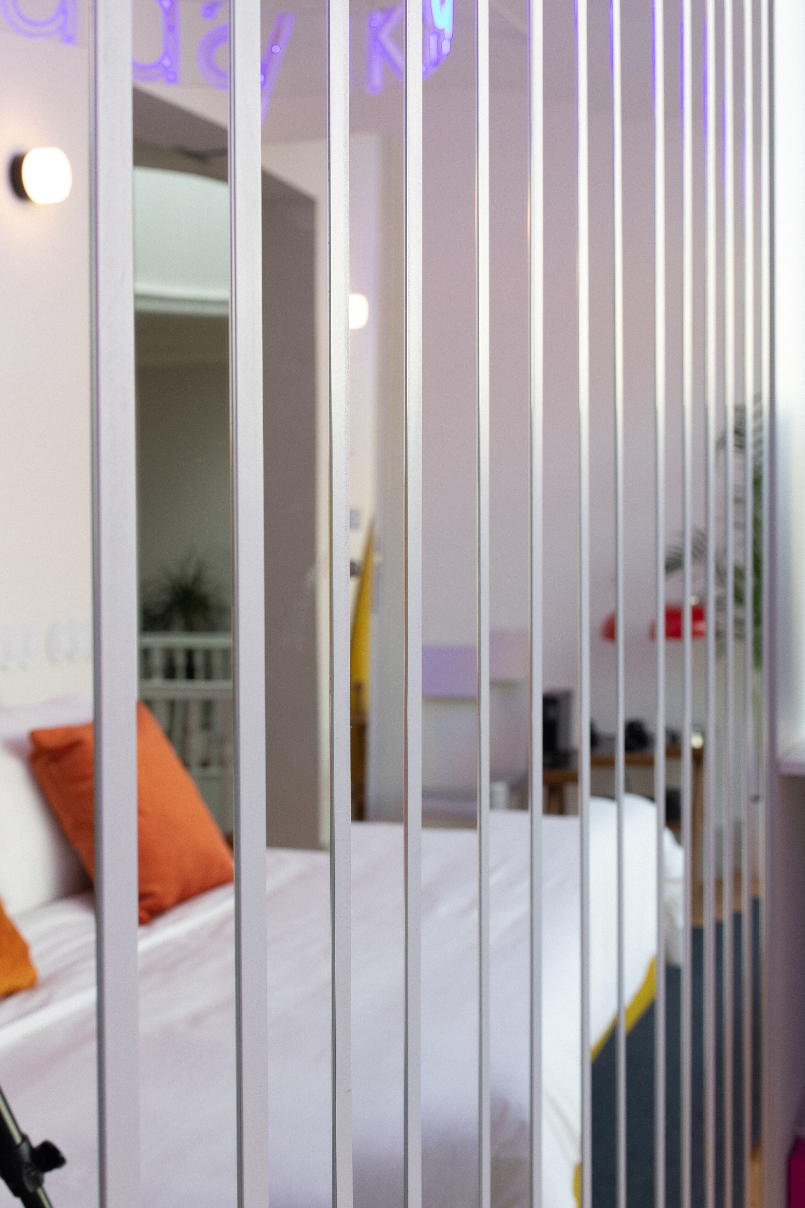 Una habitación con cama, cortinas blancas y un ventanal.