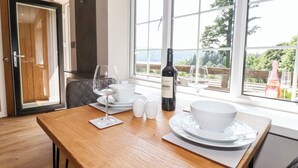 Une table à manger dressée avec de l’assiette blanche, des bols et des verres, une bouteille de vin, ainsi que des salières et des poivrières.